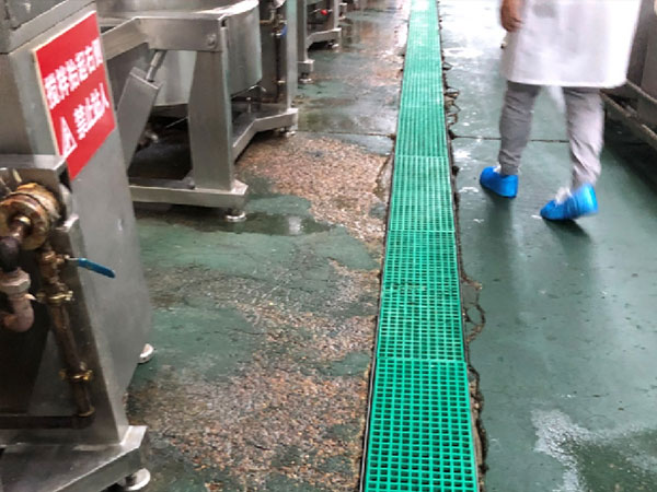 Крупный план сильного отслоения и расслоения старого эпоксидного покрытия пола в промышленной мастерской, видно, как слои отходят от основы.