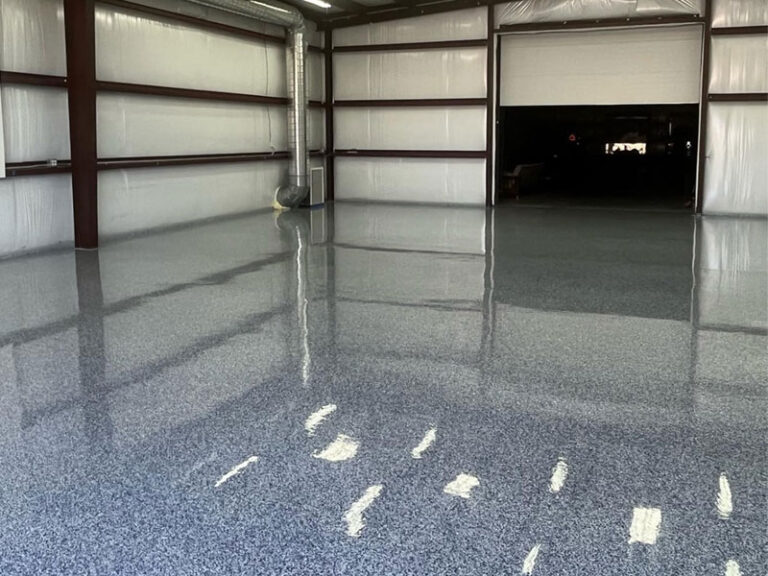 Aplicación profesional de revestimiento de poliurea gris brillante para suelos de garajes con textura antideslizante