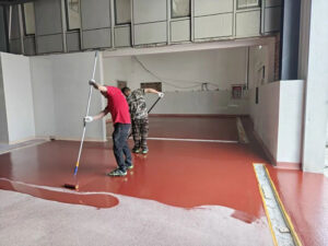 Worker using a roller to apply a finish coat to the concrete substrate, ensuring optimal adhesion for the subsequent urethane mortar floor layers.
