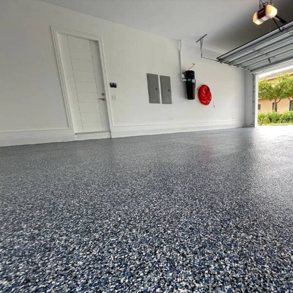 Interior view of a garage showcasing the application effect of polyurea coating on the floor, featuring a speckled, durable finish.