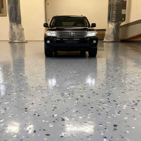 A decorative garage floor with colorful vinyl flakes embedded in a clear polyurea topcoat, providing a stylish and non-slip surface.