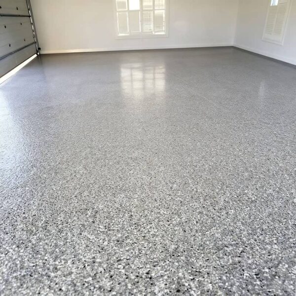 A car parked on a light gray epoxy flake garage floor, demonstrating hot tire lift resistance and durability against chemicals and heavy use.