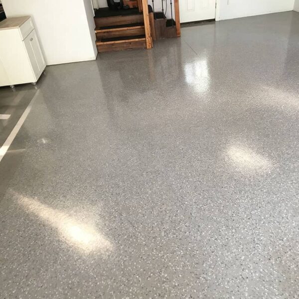 Professional epoxy coated garage floor with gray base and decorative flakes, showing full garage transformation with finished results