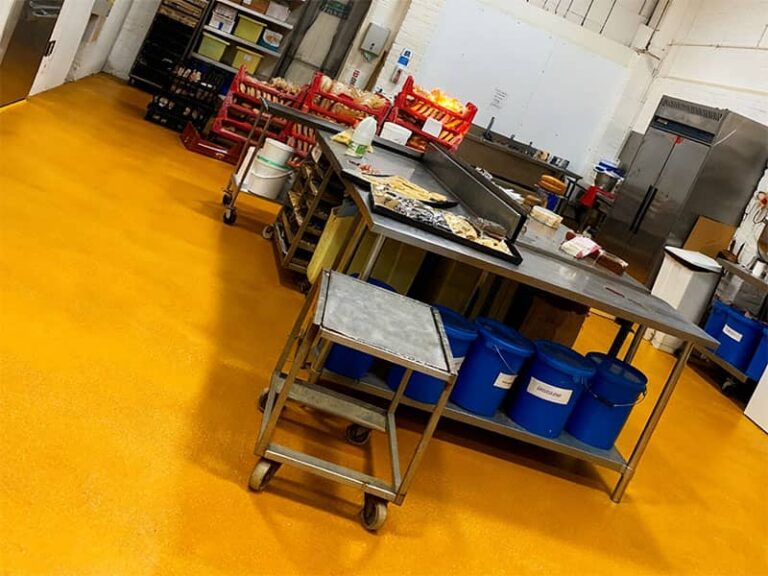 A bakery kitchen featuring yellow polyurethane (PU) flooring, highlighting its durability, slip resistance, and ease of cleaning, ideal for food preparation environments with heavy equipment and frequent spills.