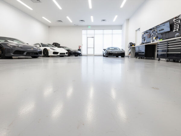 Modern luxury garage featuring high-gloss Polypro Aqua Topfloor water-based resin flooring with sports cars parked on the durable, moisture-resistant surface.