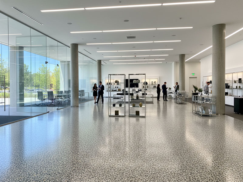A spacious commercial showroom featuring a durable, high-gloss four-layer flooring system with decorative vinyl flakes and colored quartz aggregate.