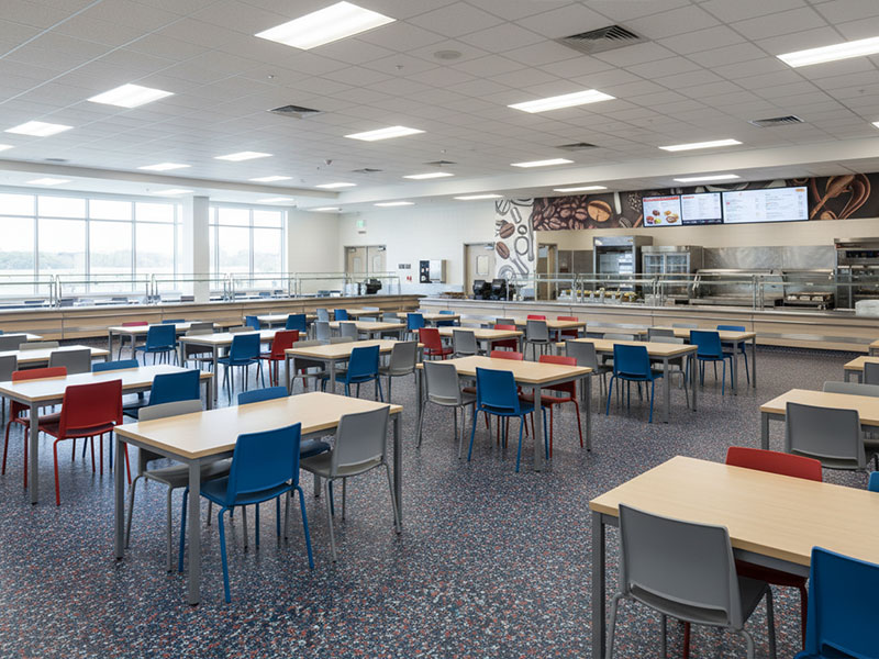 A large modern cafeteria showcasing ResuField Deco Flake BC decorative mosaic pattern epoxy flooring with vinyl chips and high-gloss finish.