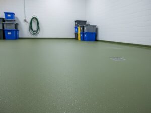 A clean industrial storage room featuring KAIDA PAINT high-performance green seamless flooring with an anti-slip texture and integrated floor drain, ideal for agricultural processing environments.