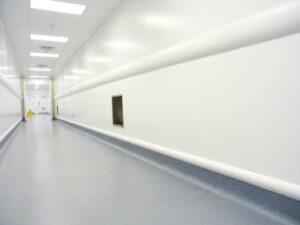 A bright, sterile pharmaceutical clean room hallway featuring KAIDA PAINT seamless and slip-resistant flooring designed for hygiene and durability in laboratory environments.