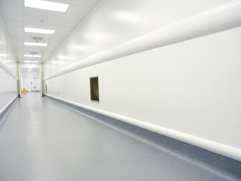 A bright, sterile pharmaceutical clean room hallway featuring KAIDA PAINT seamless and slip-resistant flooring designed for hygiene and durability in laboratory environments.