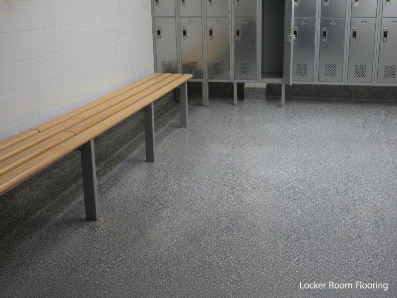 Seamless and slip-resistant gray speckled antimicrobial epoxy flooring by KAIDA PAINT in a clean commercial locker room with a wooden bench and metal lockers.
