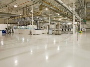 A bright and clean industrial facility featuring a high-gloss, seamless white production floor coating by KAIDA PAINT, providing a durable and safe surface for manufacturing operations.