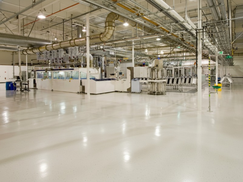 A bright and clean industrial facility featuring a high-gloss, seamless white production floor coating by KAIDA PAINT, providing a durable and safe surface for manufacturing operations.