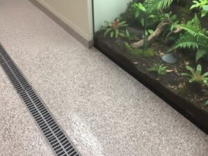 KAIDA PAINT seamless antimicrobial vivarium flooring with a decorative flake finish and integrated floor drainage system installed next to a glass animal enclosure in a research laboratory.