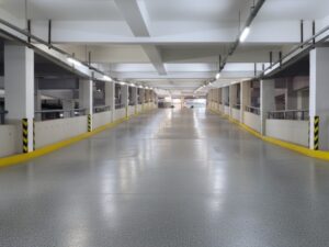Light grey speckled ramp flooring system installed in a modern, brightly lit, empty parking garage, featuring yellow safety lines and clean architectural details.