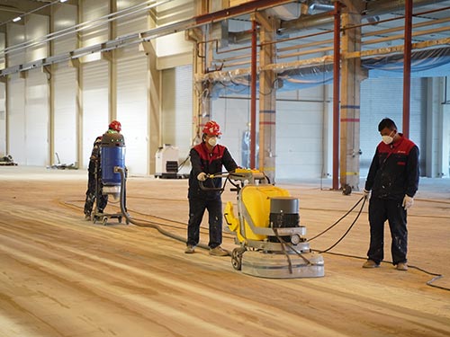 Wide perspective of the 7,000 m² factory hall in Sweden during the mechanical grinding and cleaning stage.