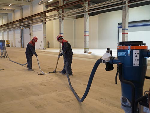 Using powerful industrial vacuums for dust-free concrete surface preparation at a Swedish industrial flooring project.