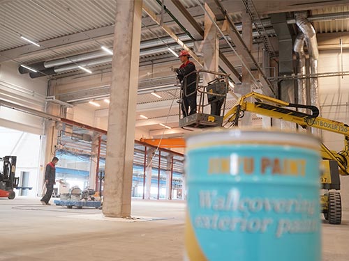 High-altitude wall spraying using professional exterior paint for an integrated factory renovation project in Sweden.