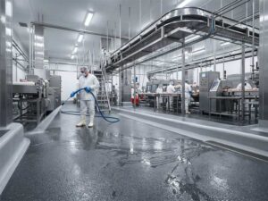 Interior of a modern food processing plant featuring seamless polyurethane cement flooring with anti-slip texture and sanitary cove base, FDA and USDA compliant.