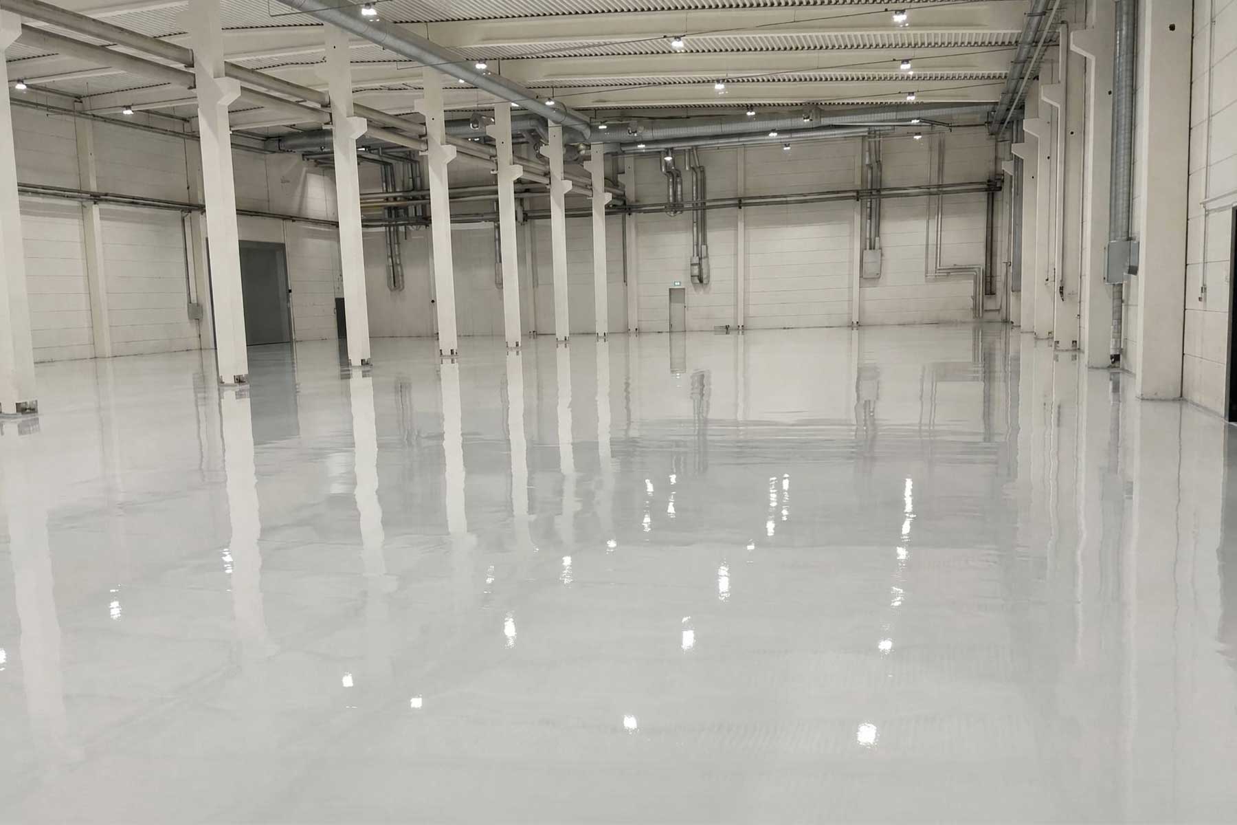 High-gloss industrial epoxy floor coating with water-based PU topcoat in a Sweden building materials processing plant renovation.