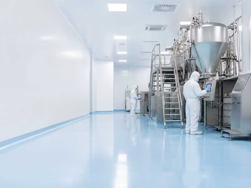 A professional hero image of a sterile GMP pharmaceutical cleanroom with engineers in white suits, featuring a seamless, high-gloss light blue epoxy flooring system