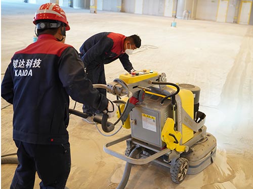 Close-up of a high-efficiency planetary floor grinder removing laitance from a concrete floor in Sweden.