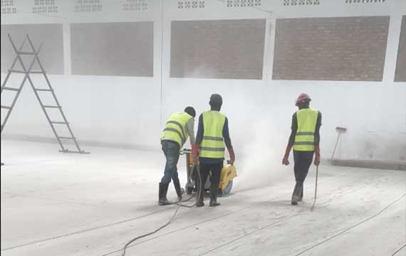 Workers cutting anchor grooves before polyurethane mortar flooring installation at a fish food processing plant in Rwanda