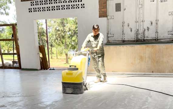 Worker grinding the floor surface before polyurethane mortar flooring installation at a fish food processing plant in Rwanda