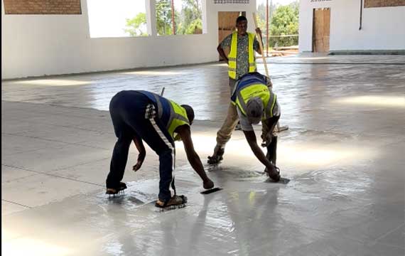 Workers applying polyurethane mortar flooring at a fish food processing plant in Rwanda