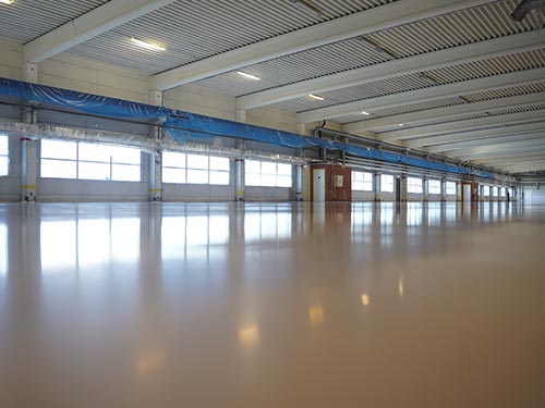 Stunning mirror-finish epoxy floor in a 7,000 sqm Swedish factory, showing clear window reflections and high gloss.