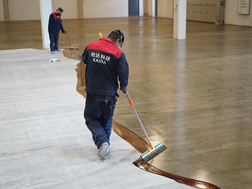 KAIDA technician applying a high-penetration epoxy primer to seal a concrete substrate in a Swedish manufacturing plant.