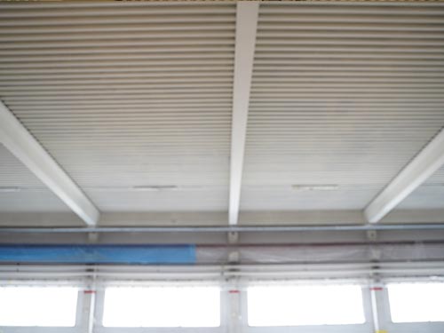 Interior view of the renovated 6,150 m² corrugated metal roof in a Swedish factory, featuring high-durability white protective coating.