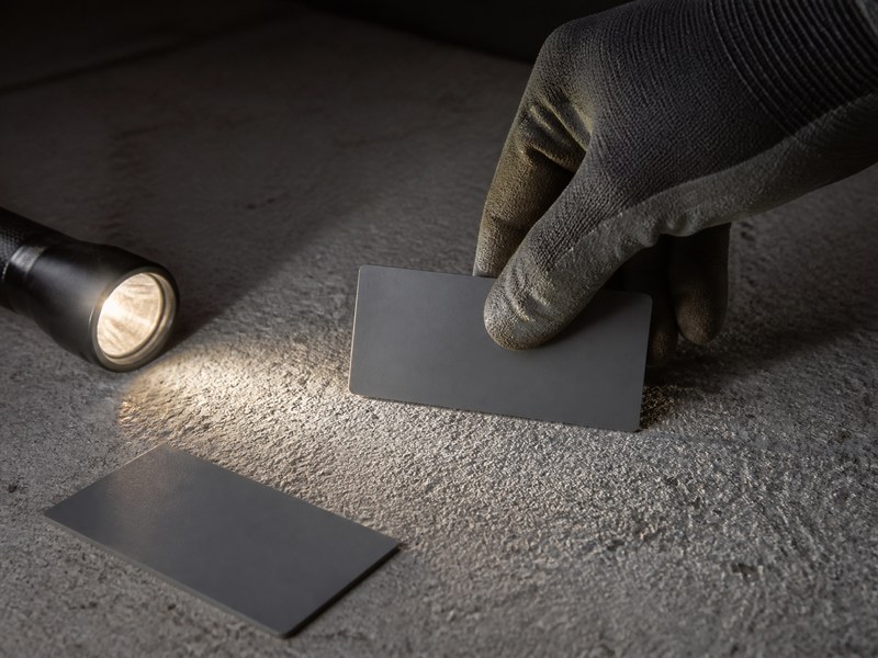 Coating inspector comparing an ICRI CSP comparator chip to a shotblasted concrete floor under raking flashlight light