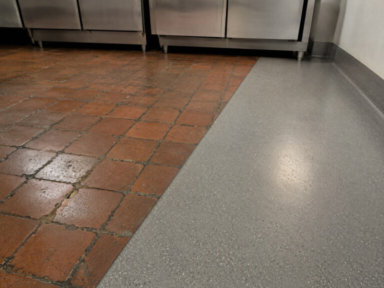 Split view of a commercial kitchen floor: worn clay tiles with dark eroded joints on one side, seamless resin with a coved edge on the other