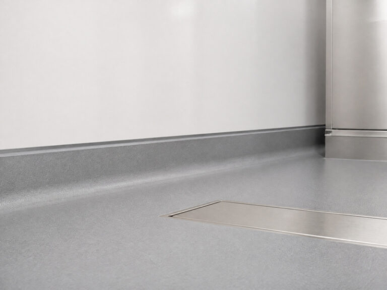 Finished 75 mm coving detail in a wet process room: a continuous resin cove joining a smooth hygienic wall panel to a dry resin floor, with a clean sealed head joint.